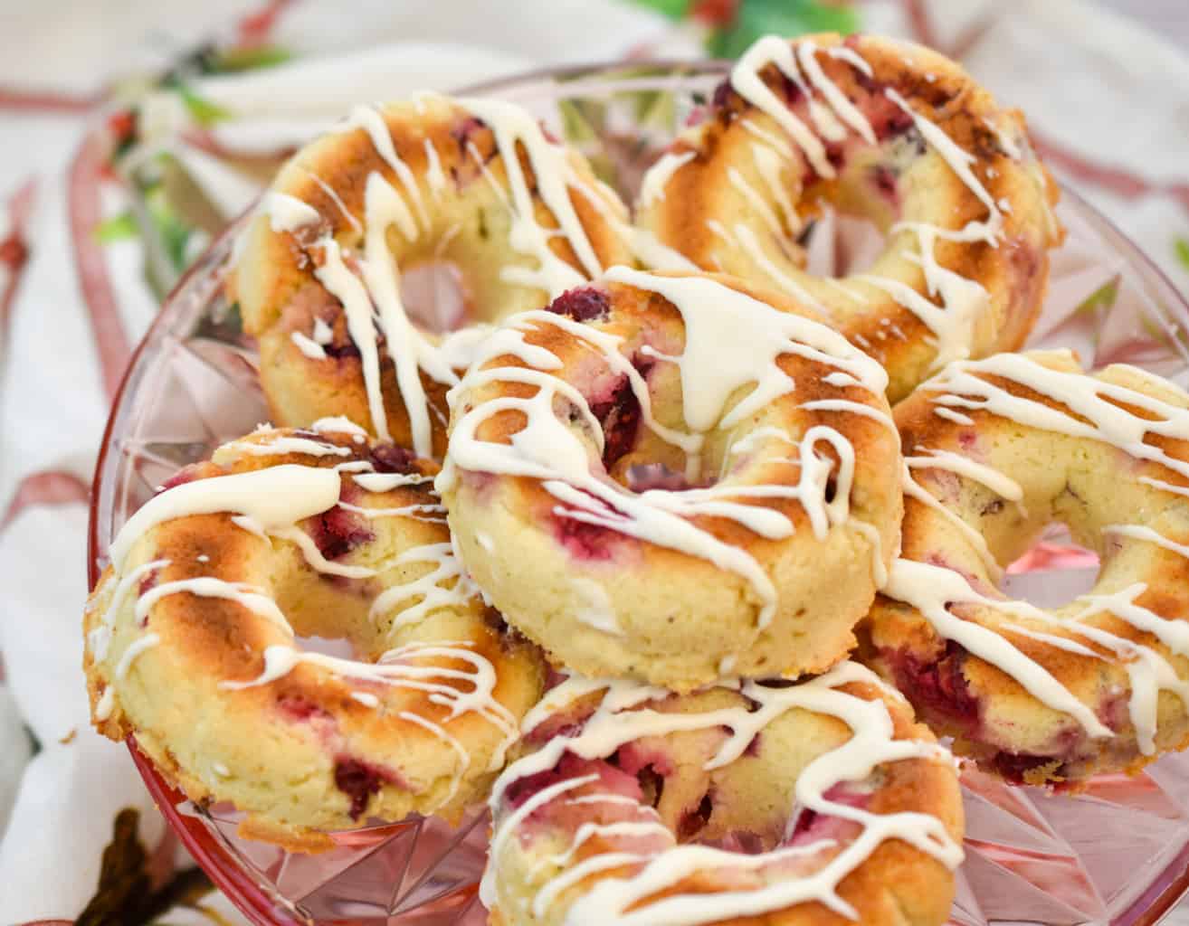 keto cranberry donuts stacked on a pink clear plate