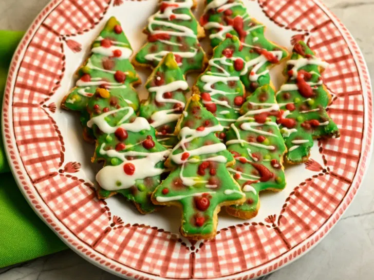 keto Christmas tree sugar cookies stacked on a red and white plate