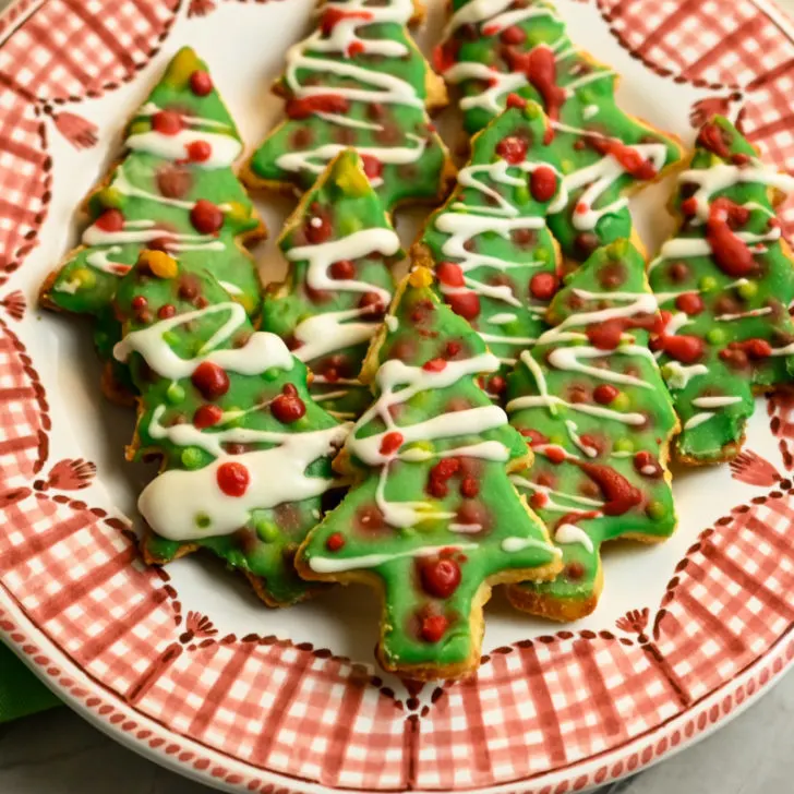 keto Christmas tree sugar cookies stacked on a red and white plate