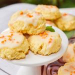 keto orange cookies on white pedestal with more cookies in the background