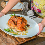 Keto Cuban Mojo Chicken on white plate being placed on wood trivet on table