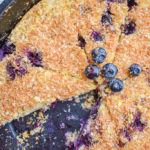 keto blueberry toasted coconut skillet cake in cast iron skillet with one slice missing close up