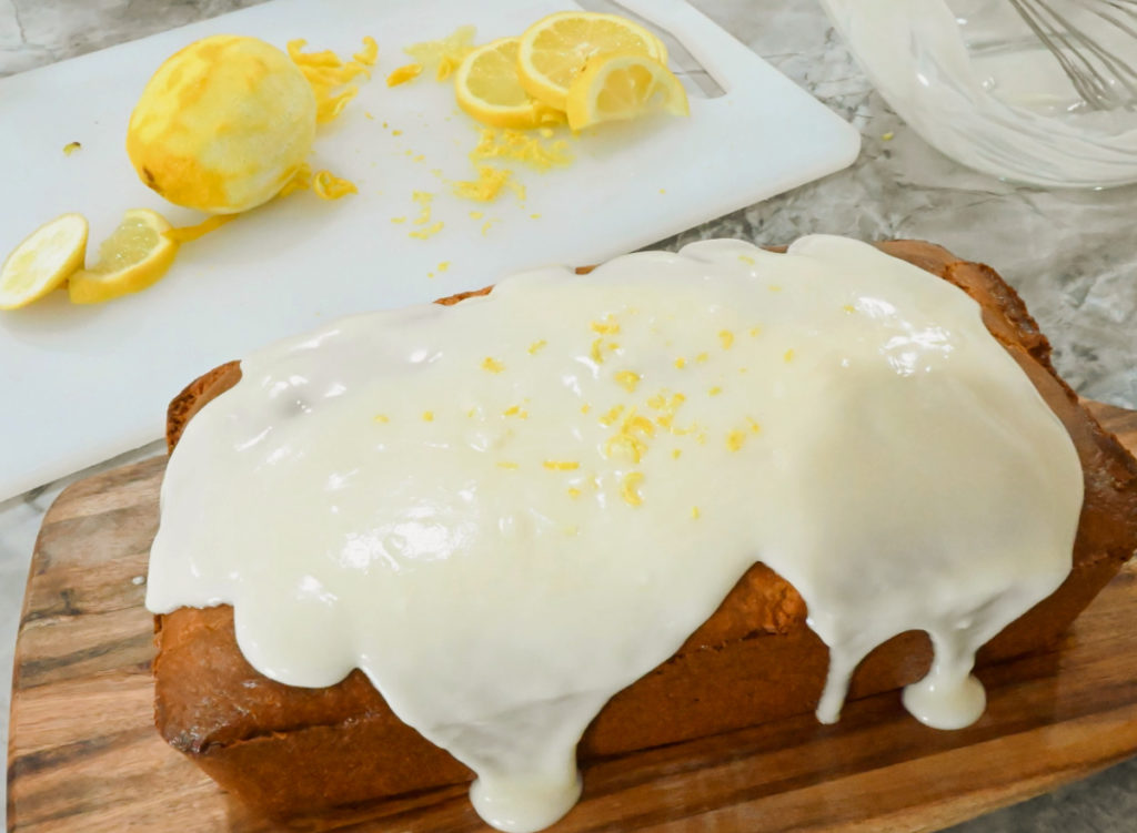 keto lemon pound cake being topped with lemon zest