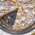 keto raspberry white chocolate scones in cast iron skillet cut into slices with one slice removed up close