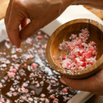 Crushed sugar free peppermint candies being sprinkled on keto chocolate bark