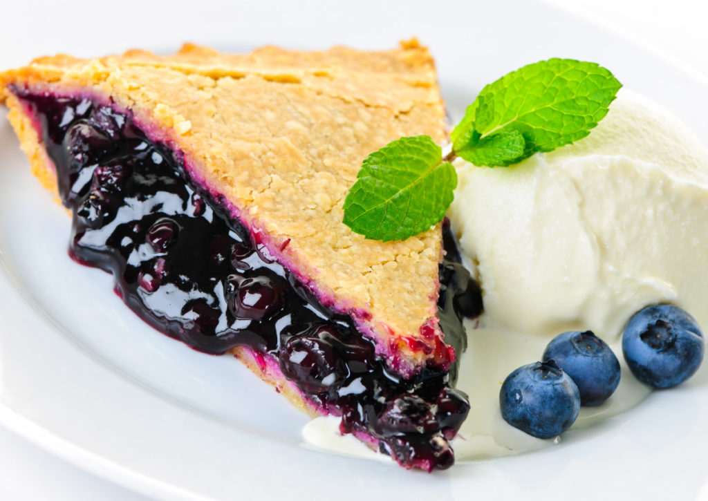 Slice of keto blueberry pie with sugar-free vanilla ice cream and berries