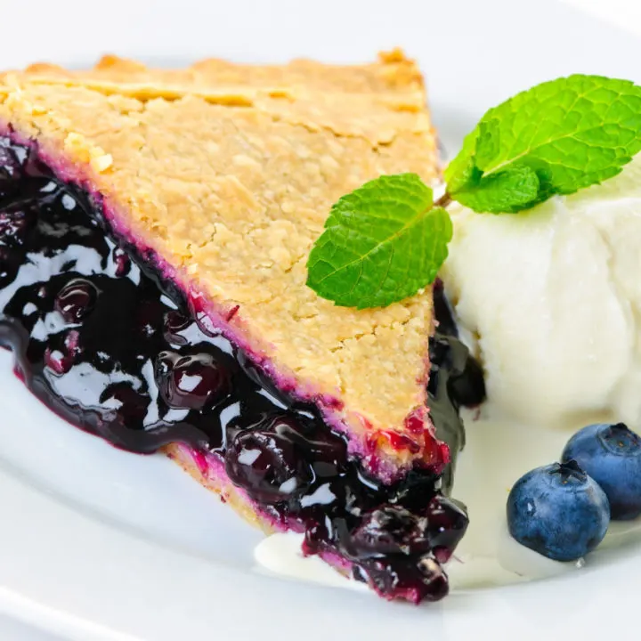 Slice of keto blueberry pie with sugar-free vanilla ice cream and berries